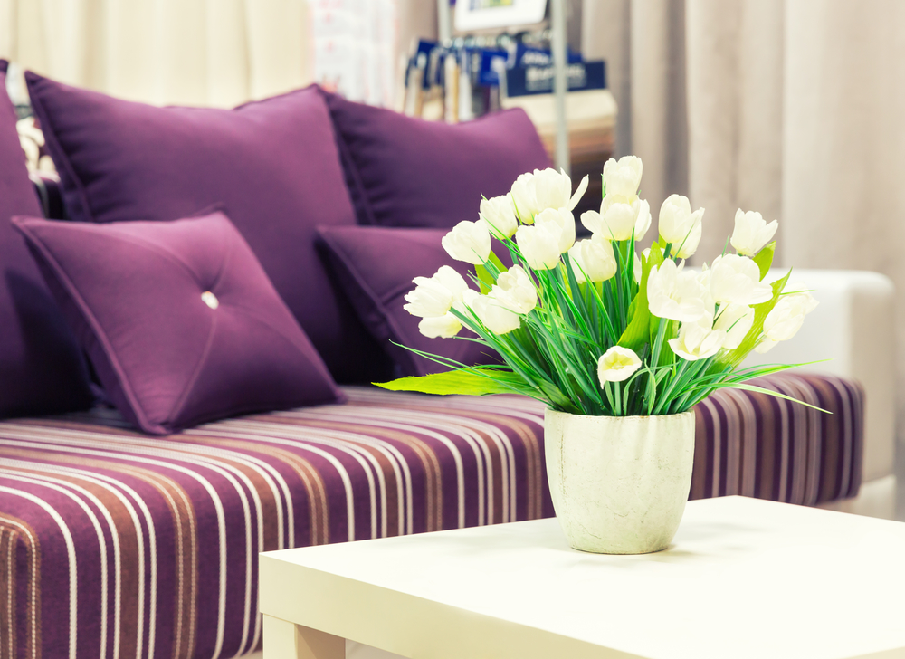 Flowers in a vase against sofa with velvet pillows